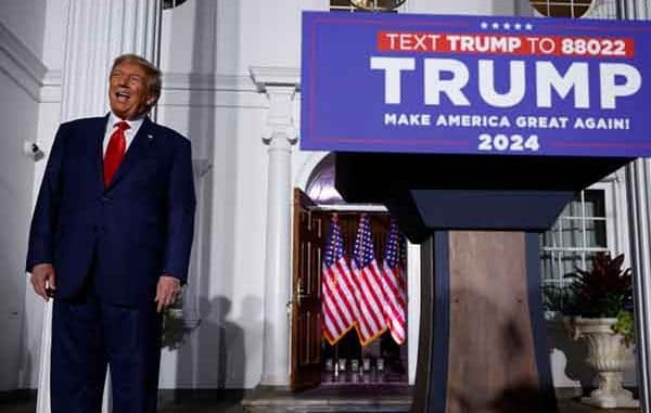 Donald Trump standing next to a 2024 campaign podium
