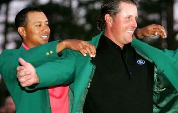 Tiger Woods putting a green jacket on Phil Mickelson at The Masters