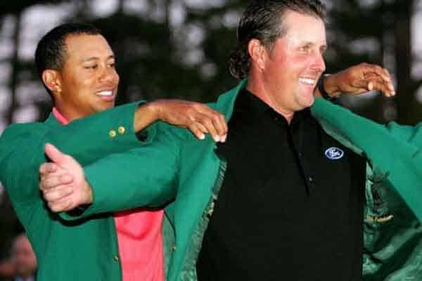 Tiger Woods putting a green jacket on Phil Mickelson at The Masters